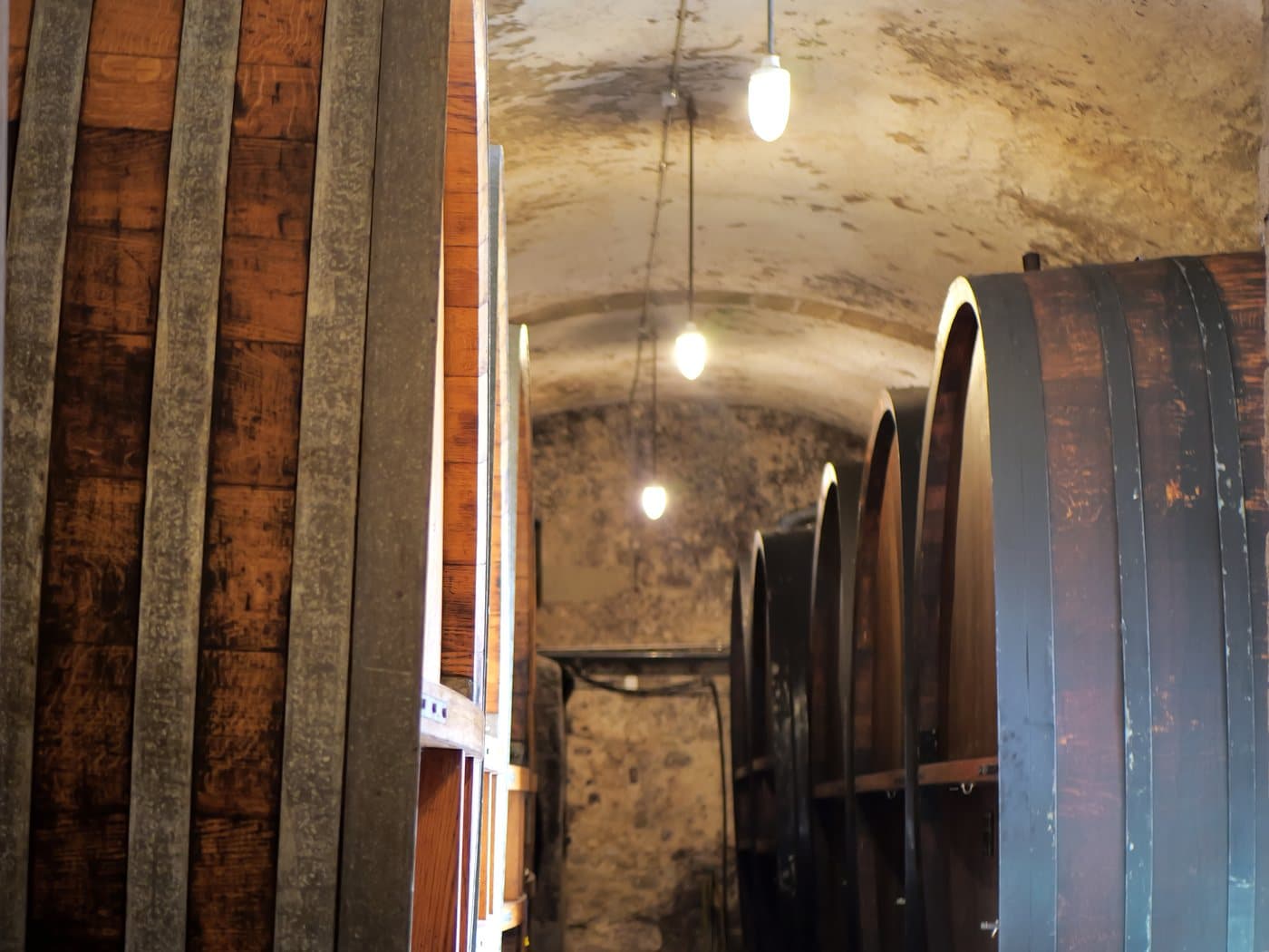 L'allée des grands foudres en bois, sous les voûtes éclairées de la cave du château.