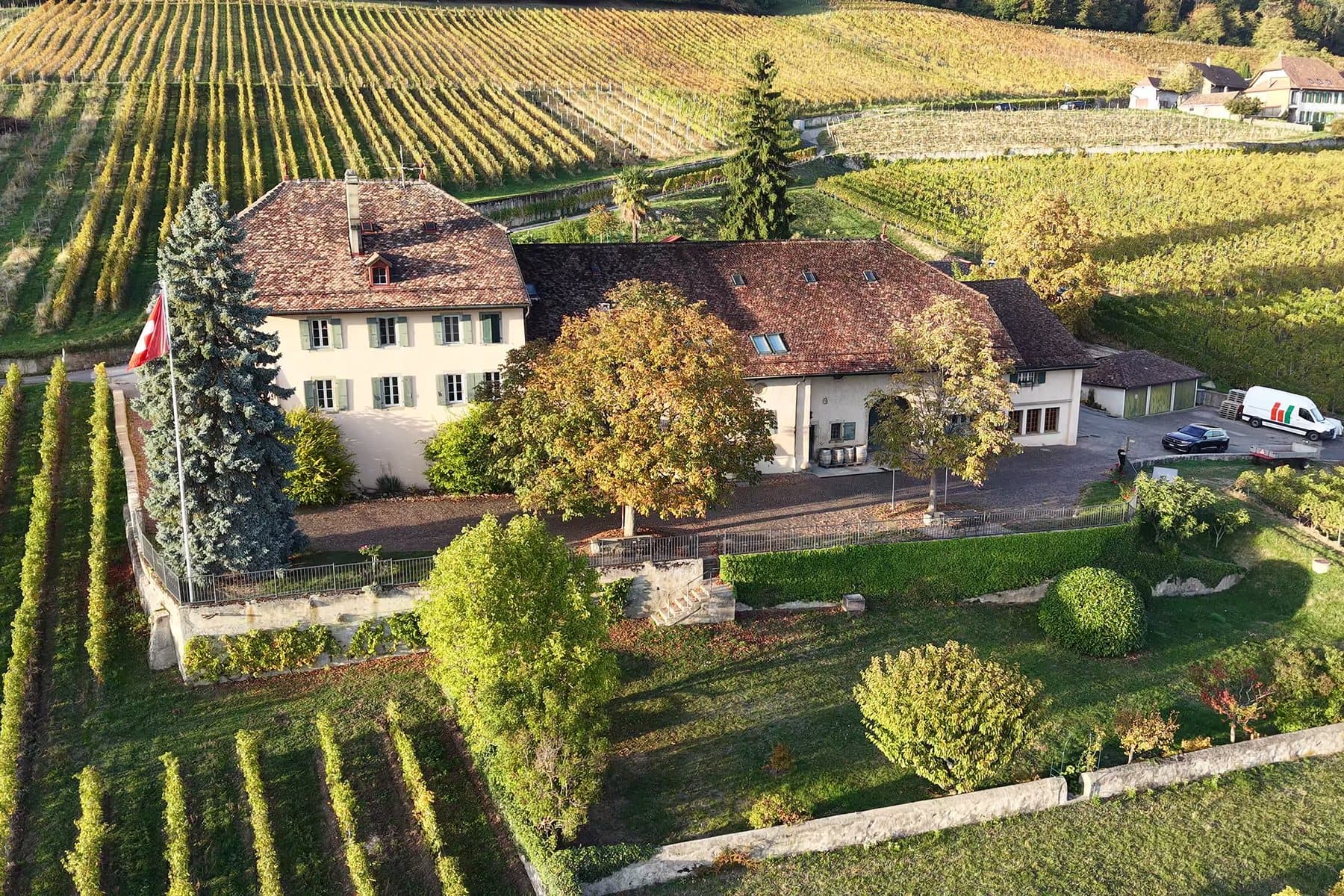 Le Domaine de Sarraux-Dessous vu du ciel au coucher du soleil, entouré de ses vignes d'automne.