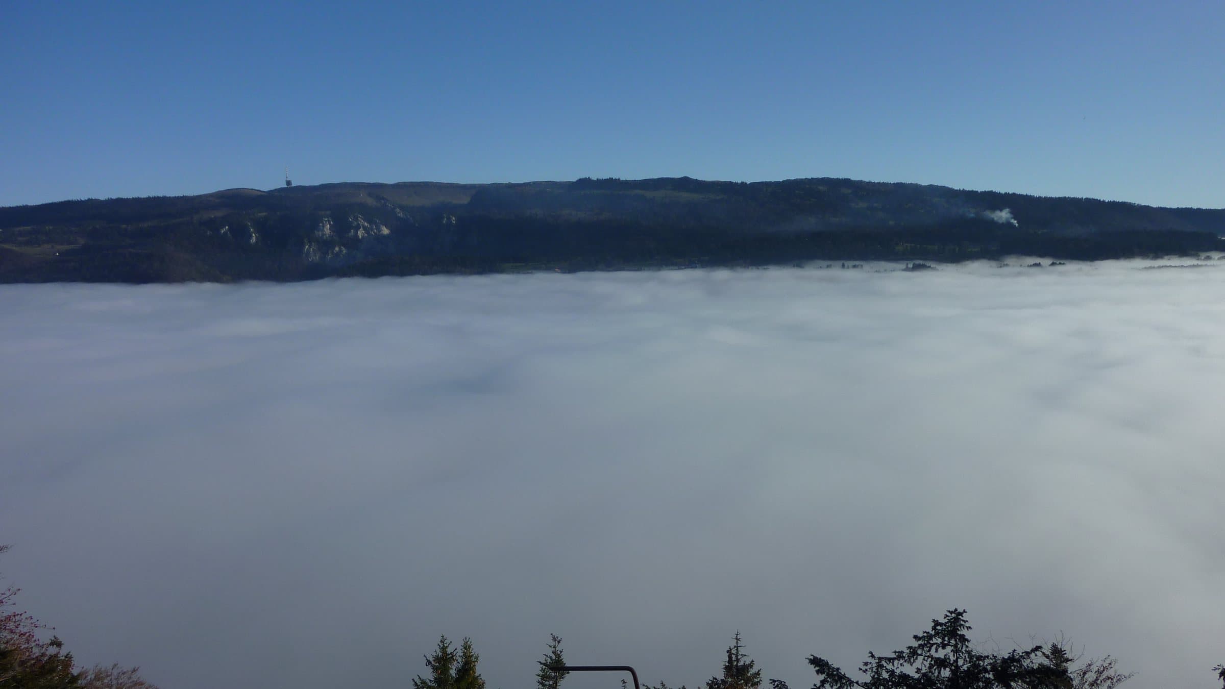 La mer de brouillard vue de Mont-Soleil, sous un ciel bleu, avec les crêtes du Jura en face.