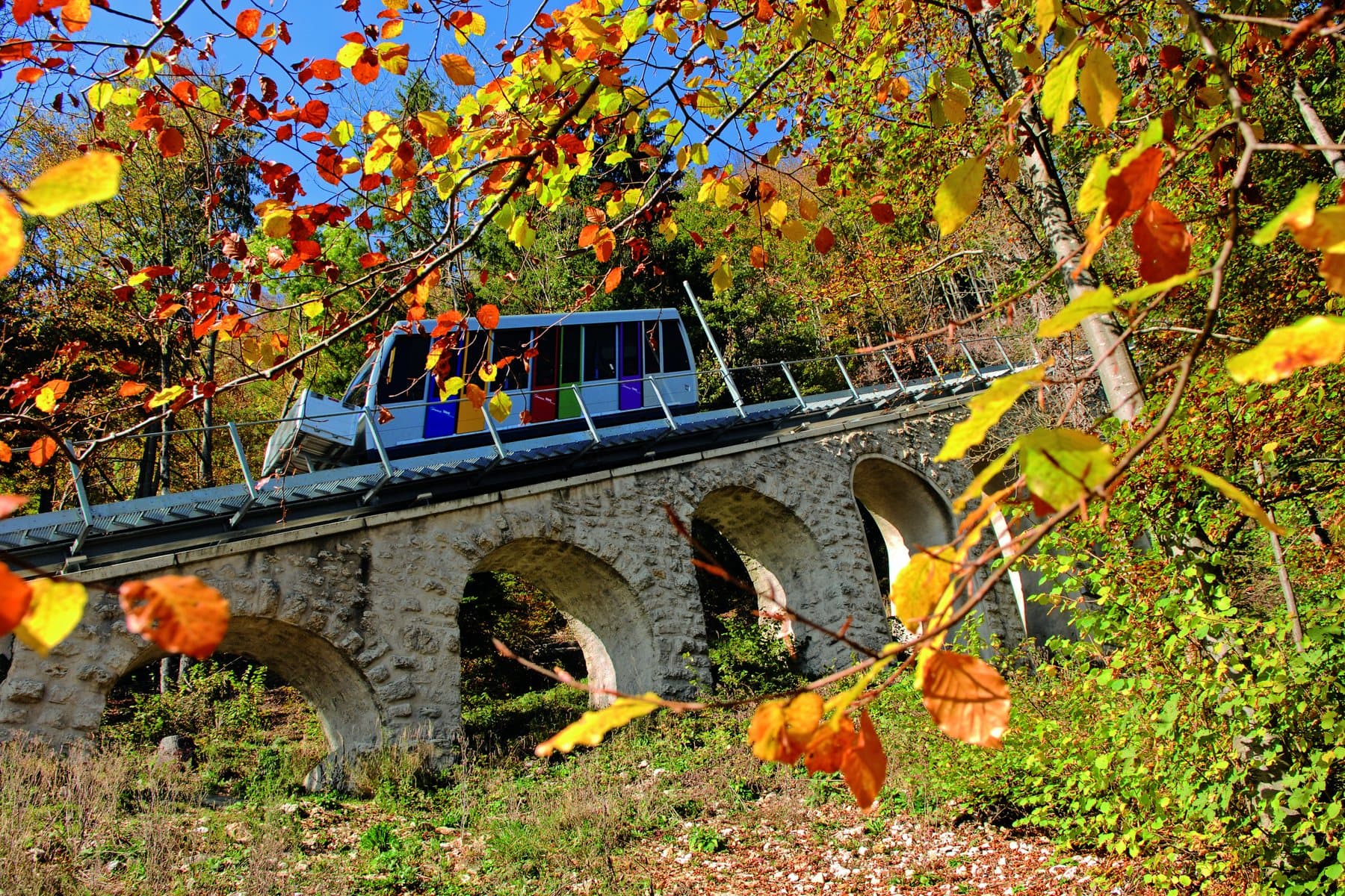 La voiture du funiculaire sur son viaduc de pierre, entre les feuillages d'automne.