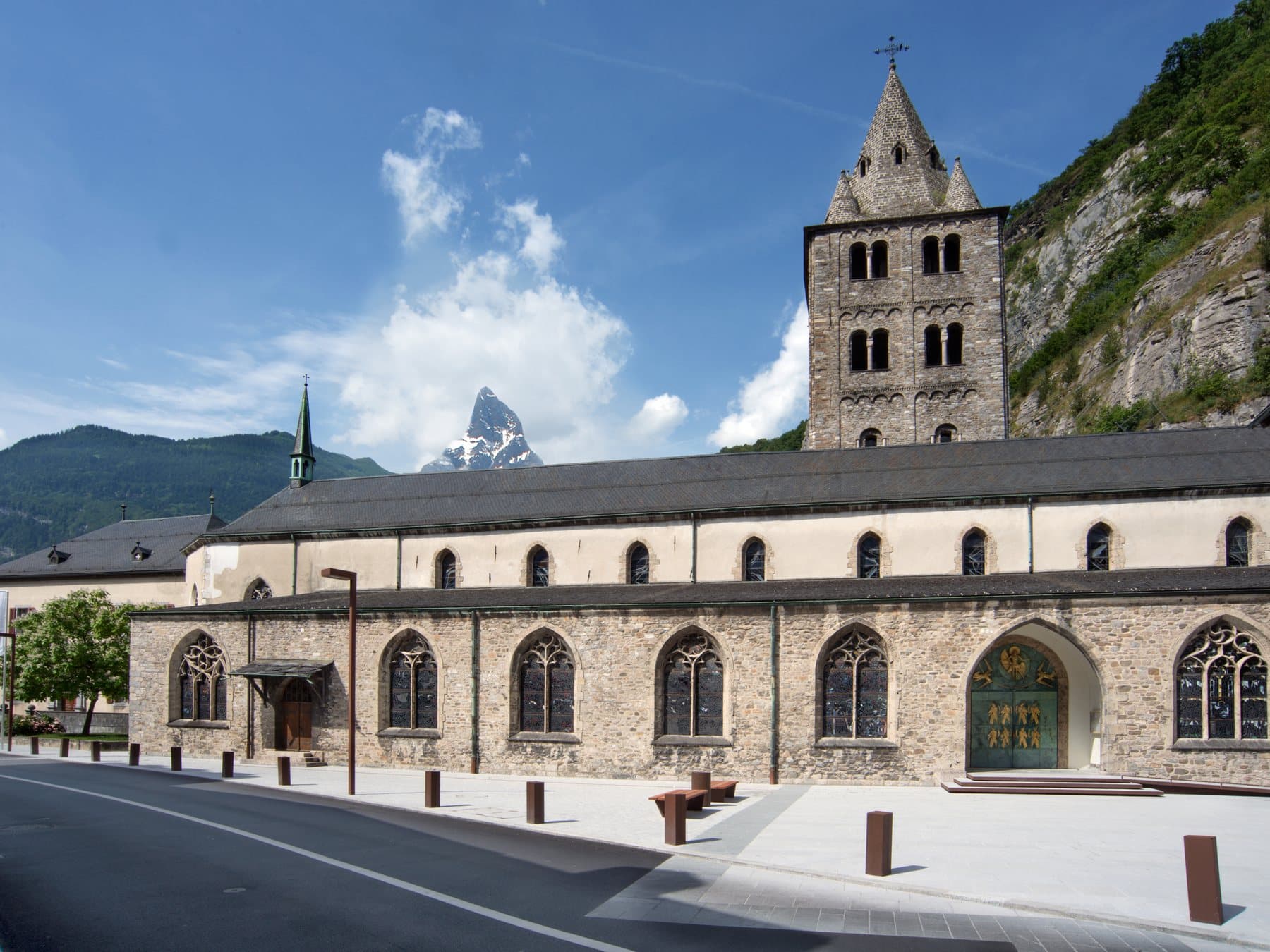 La façade de la basilique de Saint-Maurice et son clocher roman, contre la falaise.
