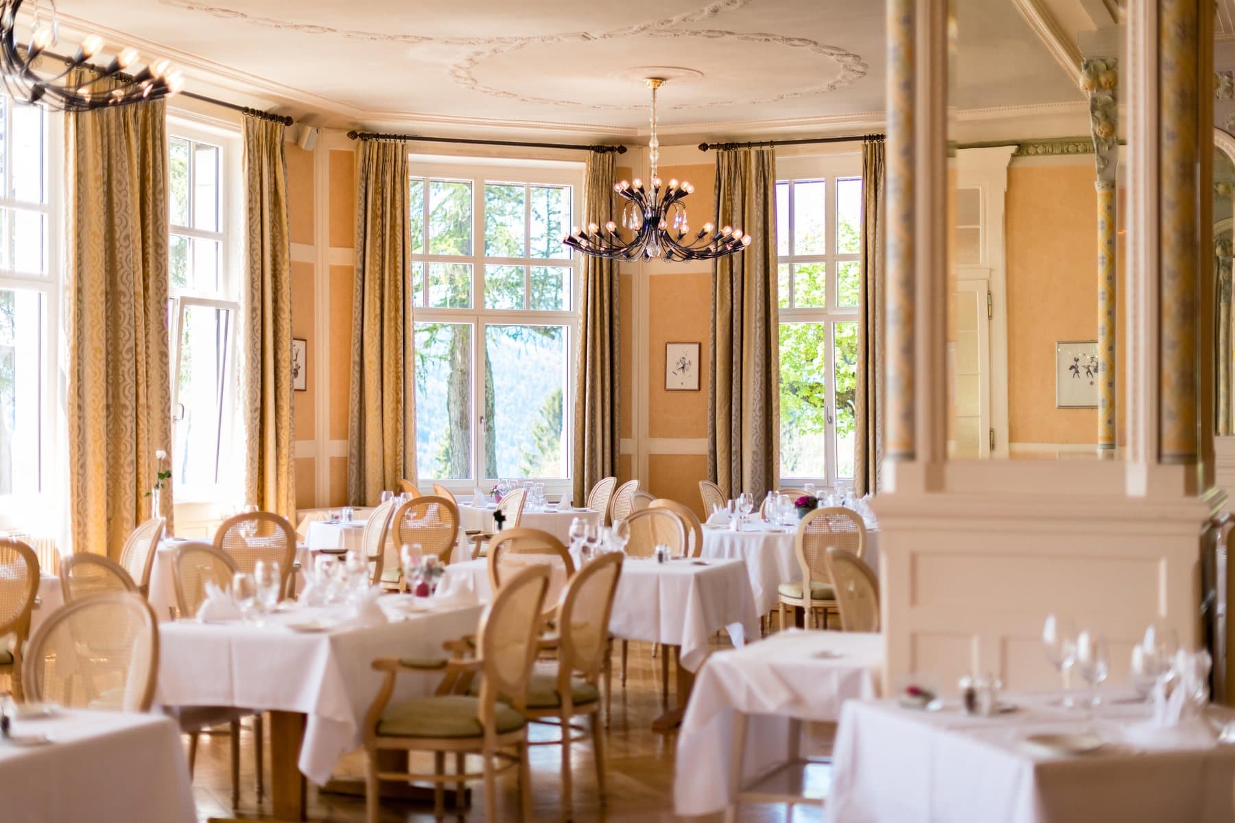La salle Belle Époque du Grand Hôtel des Rasses, ses colonnes, ses lustres et ses tables dressées.