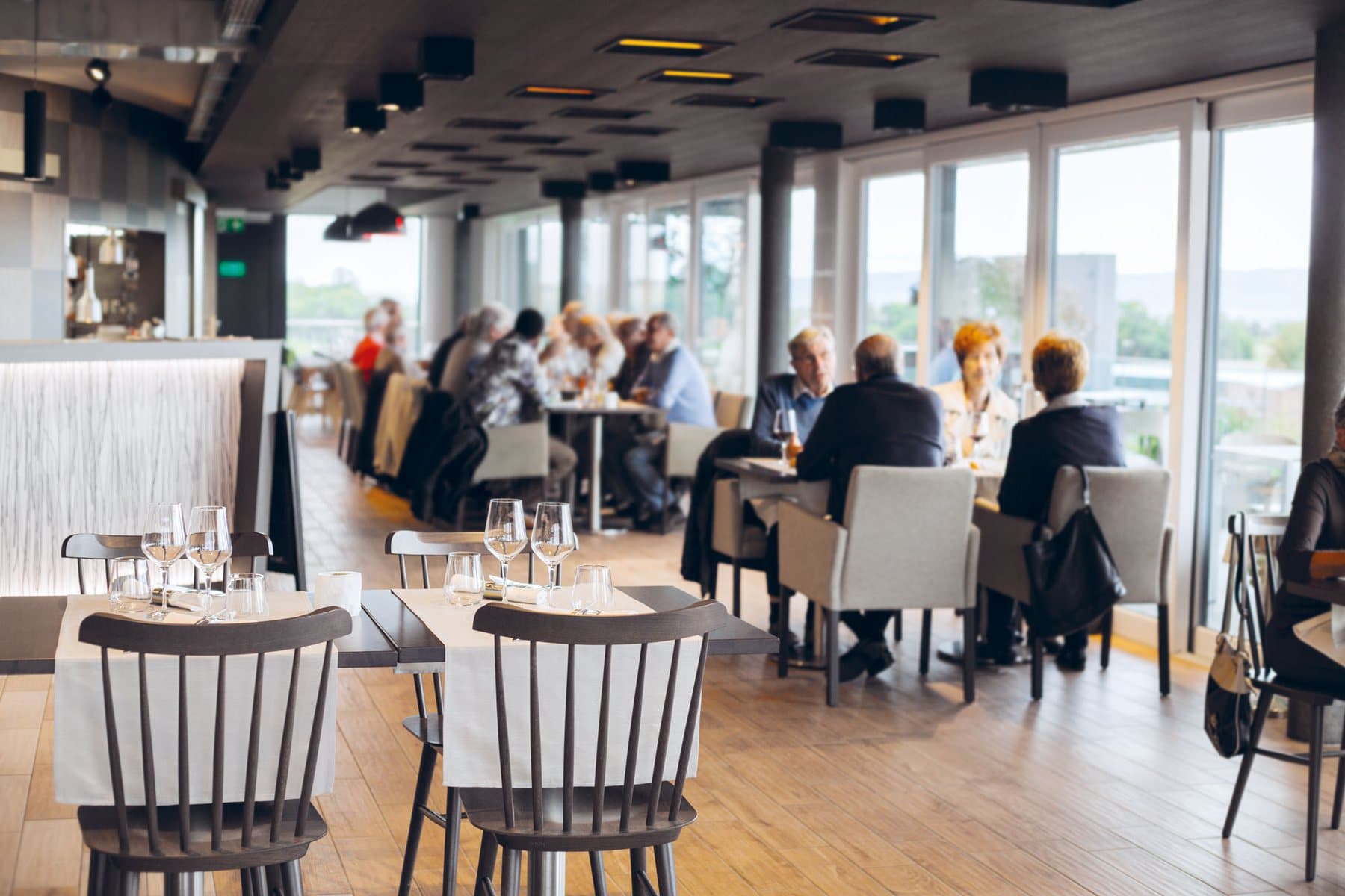 La salle du restaurant Le 1424 et ses baies vitrées sur le lac de Neuchâtel.