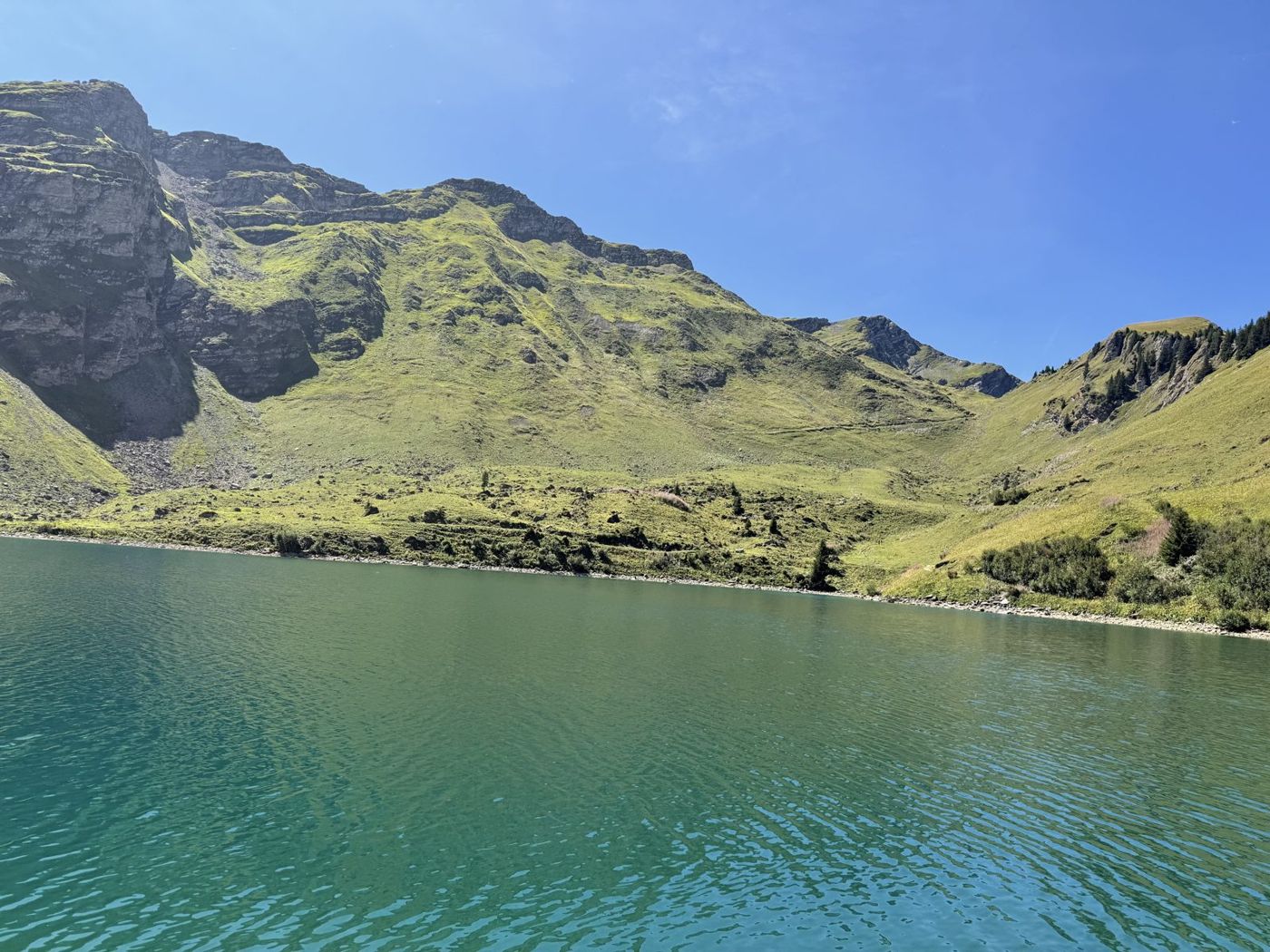 Le lac de Lyrette, turquoise, entre des pentes herbeuses